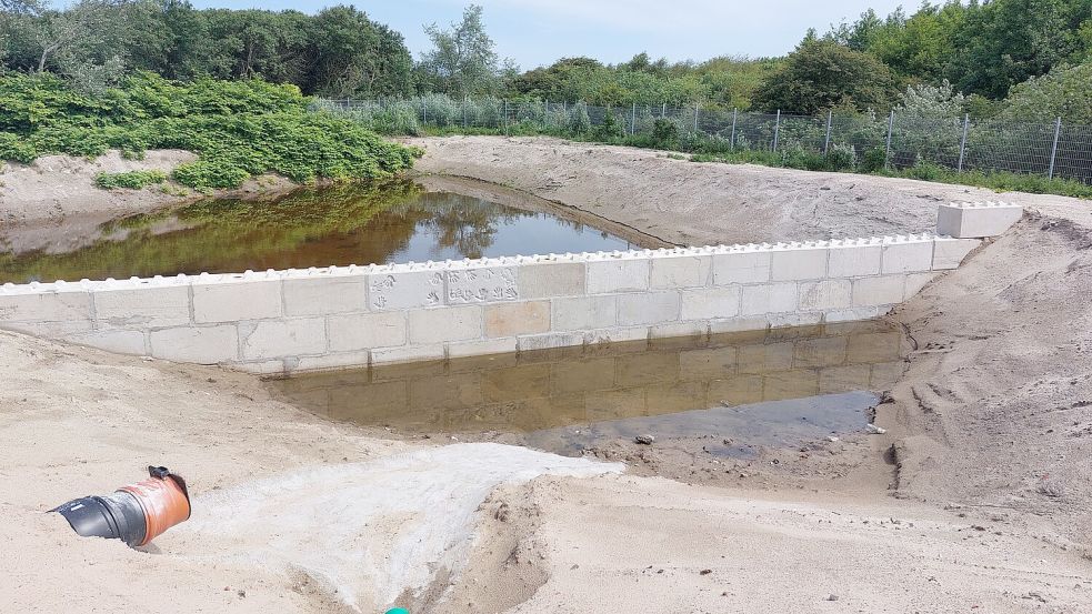 Der Spülteich auf der Außenanlage. In der Mauer haben sich zahlreiche an dem Projekt Beteiligte mit einem Handbadruck verewigt. Foto: Ferber