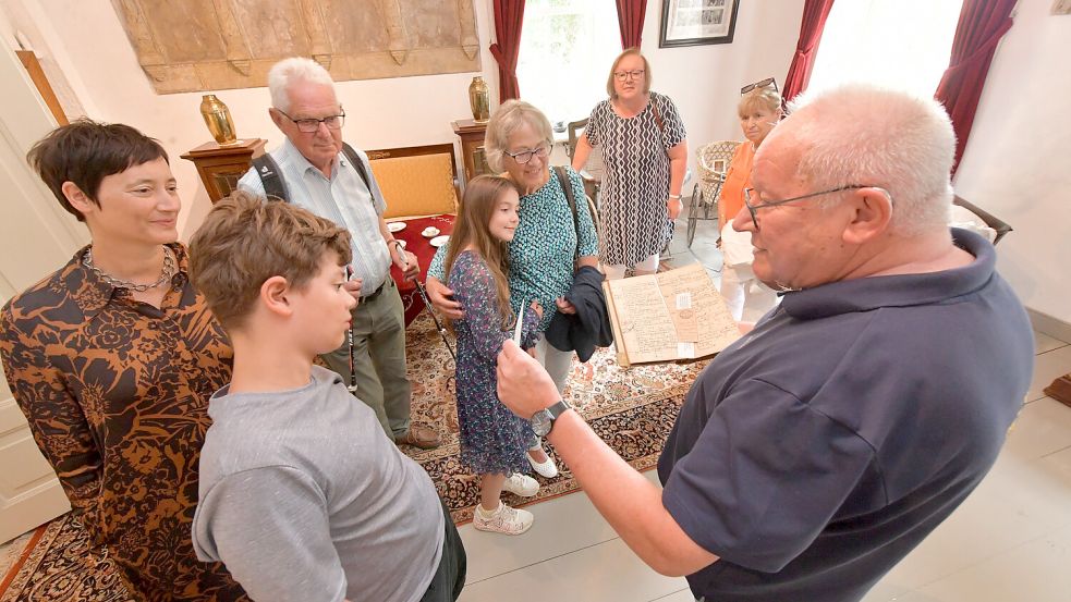 Der Vorsitzende des Krummhörner Heimatvereins, Menno Müller, zeigt der Familie Ausstellungsstücke über ihre Vorfahrin. Foto: Ortgies