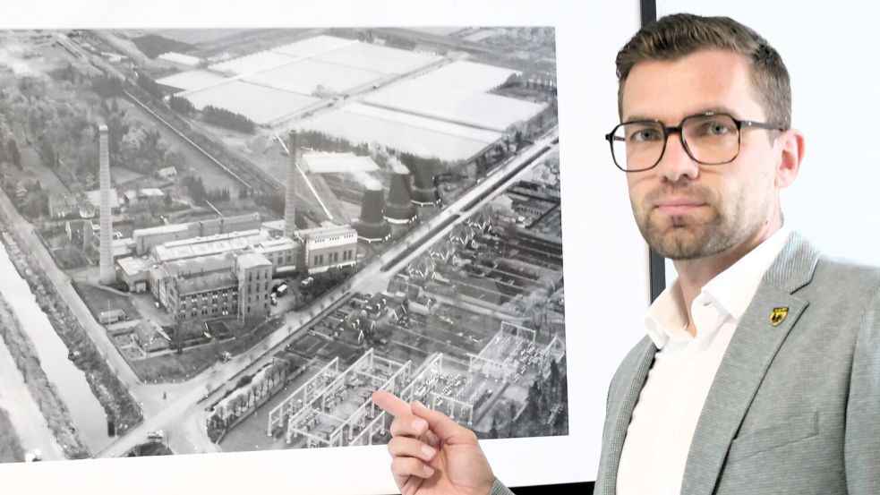 Bürgermeister Sven Lübbers (parteilos) vor einer Aufnahme des alten Wiesmoorer Kraftwerks und des heute noch bestehenden Umspannwerks. Anstelle des Kraftwerks stehen heute das Rathaus und die Sparkasse. Foto: Böning
