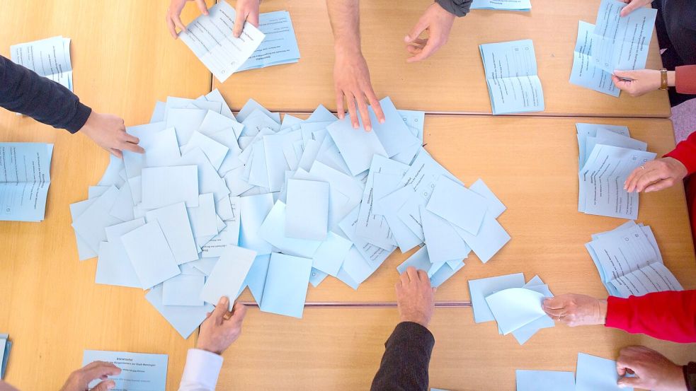 Alle helfen mit: Auszählung der Urnen-Wahlscheine. Foto: Reichel/dpa