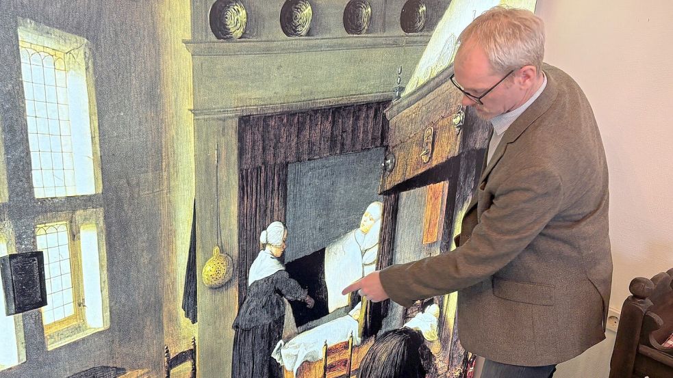 Oliver Freise, Leiter des Heimatmuseums in Leer, erklärt was auf dem ausgestellten Gemälde zu sehen ist. Foto: Vogt