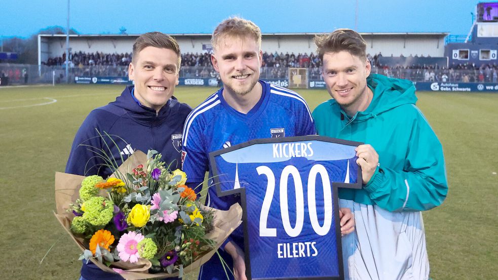 Vor seinem 201. Pflichtspiel für Kickers erhielt Marvin Eilerts noch eine Ehrung für sein 200. Spiel beim jüngsten 2:1 in Kiel. Teammanager Bastian Dassel (links) und der Sportliche Leiter Henning Rießelmann ehrten das Urgestein, das seit 2017 in Emden spielt. Foto: Doden/Emden