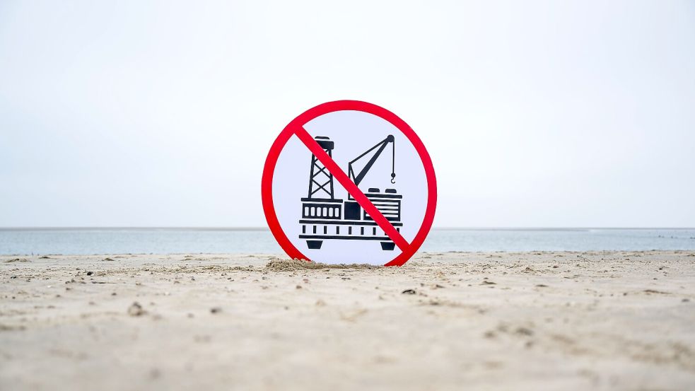 Ein Plakat gegen die Erdgasförderung steht am Strand von Borkum. Foto: Schuldt/dpa