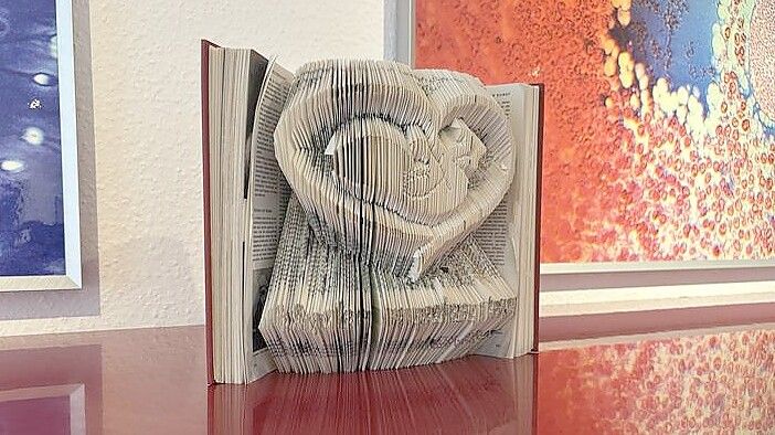 Ein Baby in einem Herz - geschnitten in die Seiten eines Buches. Auch das ist eines von vielen Geschenken, die in der Praxis von Dr. Grita Hasselbach in Leer steht. Foto: Nobel