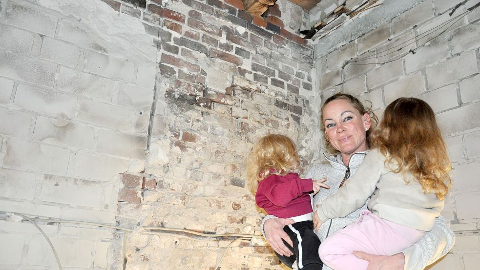 Selina Linke steht mit ihren Töchtern Mayla (links) und Malou auf dem Arm in der Küche. Im Juli 2023 war ungefähr an dieser Stelle der Brandherd. Foto: Ullrich