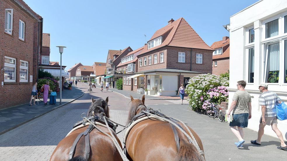 Gemütliche Insel Juist: Eine Pferdekutsche fährt durch die Straßen des Ortes. Foto: dpa/Carmen Jaspersen