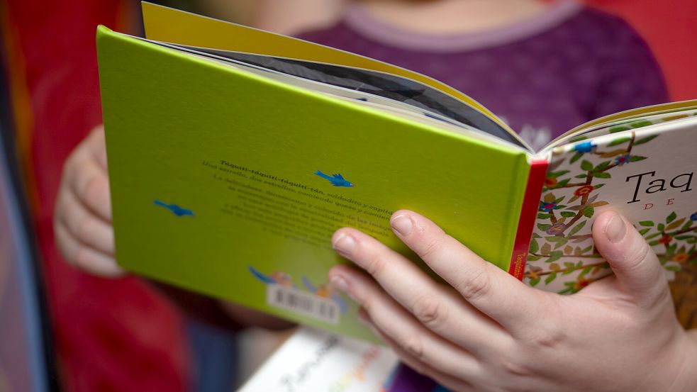 Eine Mutter liest ihrer Tochter im Kinderzimmer aus einem Buch vor. Foto: Fernando Gutierrez-Juarez/dpa
