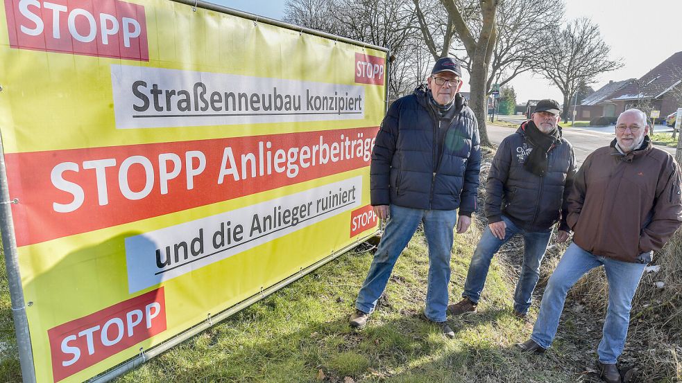 Seit Beginn des Jahres wehren sich Anwohner der Dorfstraße Klein-Hesel öffentlich gegen die Beiträge zur Sanierung der Straße. Hier die BI-Mitglieder Robert Preyk (von links), Uwe Türbsch und Detlef Preyk mit einem der Plakate. Foto: Klaus Ortgies/Archiv