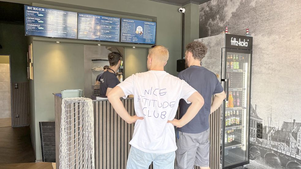 Die Speisekarte ist an der Wand auf Bildschirmen erkennbar. An der Bestelltheke wird das Essen geordert. In die Küche hat man vollen Einblick.