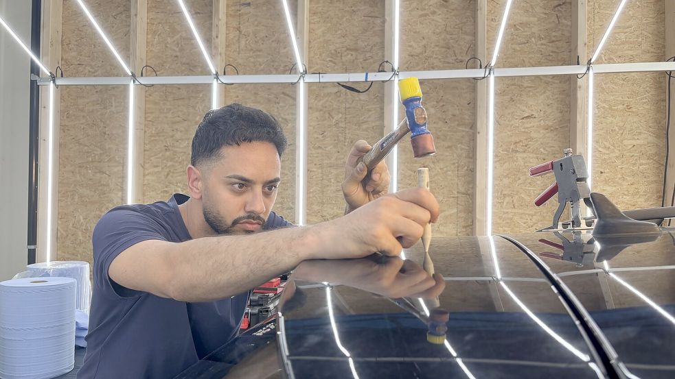 Mücahit Payik ist für die Reparatur der Autos zuständig. Mit verschiedenen Methoden bessert er die Dellen aus. Foto: Leona Spindler