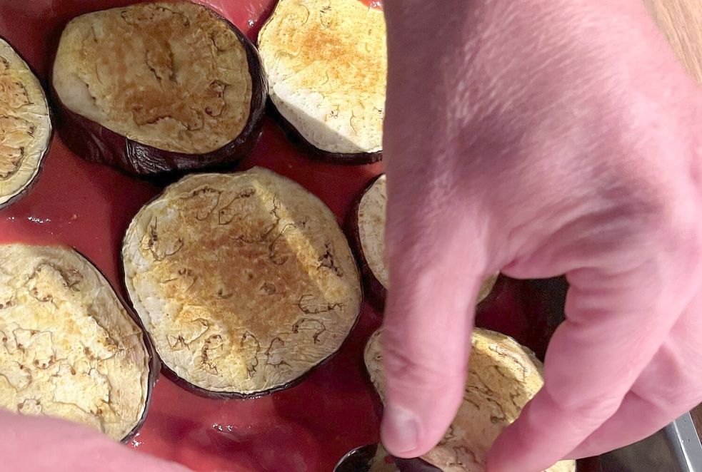 Erst die Soße, dann Auberginenscheiben: Der Anfang ist gemacht, es folgen noch die Tomatenscheiben und Käse. Foto: Carmen Leonhard