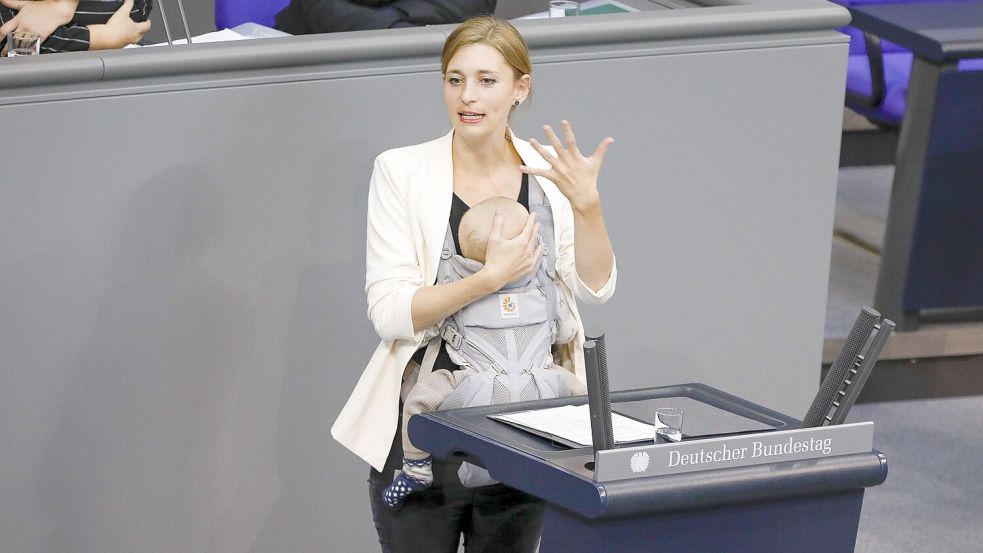 Die Abgeordnete Hanna Steinmüller (Grüne) spricht mit ihrem schlafenden Baby in der Trage am Rednerpult des Deutschen Bundestags. Foto: IMAGO / pictureteam