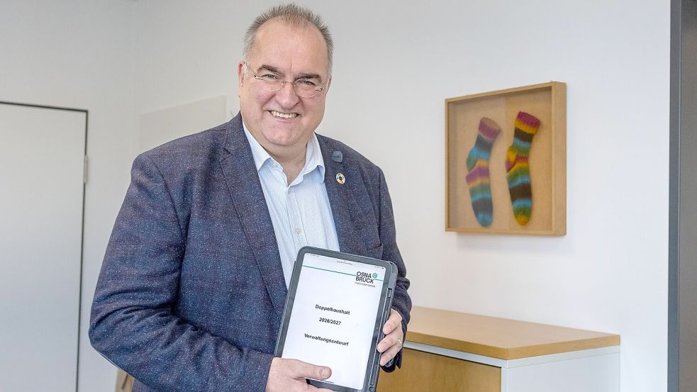 Osnabrücks Kämmerer Thomas Fillep mit dem digitalen Haushaltsentwurf – vor den „Sparstrümpfen“ in seinem Vorzimmer. Foto: Denise Matthey