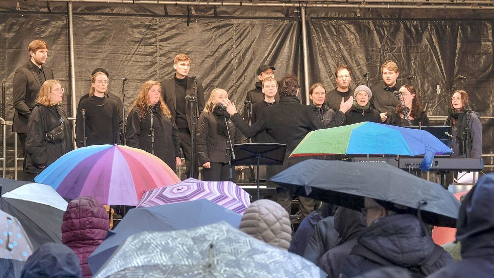 Die Chöre standen beim Friedenssingen auf der Bühne im Trockenen, die Teilnehmer spannten vor der Bühne ihre Schirme auf. Foto: Thomas Osterfeld