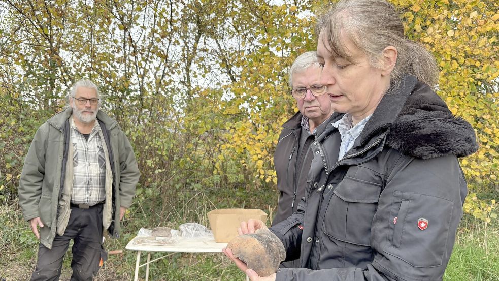 Dr. Sonja König (von rechts) zeigt dem Marxer Ortsvorsteher Arthur Engelbrecht eine der rund 1000 Jahre alten Tonscherben, die das Team der Landschaft hier bereits gefunden hat. Grabungsleiter Axel Prussat leitet das Grabungsteam in Friedeburg. Foto: Susanne Ullrich