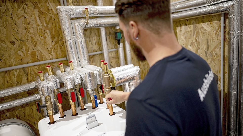 Ein Handwerker arbeitet an einer Wärmepumpe. Foto: Fabian Sommer/dpa