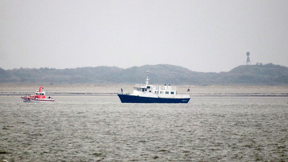 Ein Schiff der Seenotretter und das Beerdigungsschiffvor der Insel Juist. Foto: Volker Bartels/dpa +++ dpa-Bildfunk +++