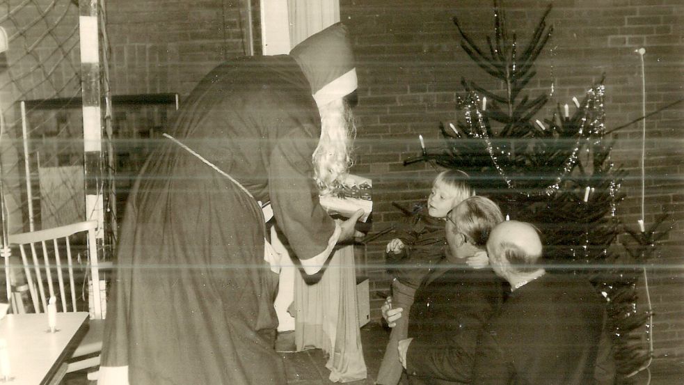 In den 1970er Jahren überreichte der Weihnachtsmann den Kindern in der Deterner Turnhalle Geschenke. Ralf Möhlmann nahm sein Geschenk aus den Armen seines Opas entgegen. Foto: privat