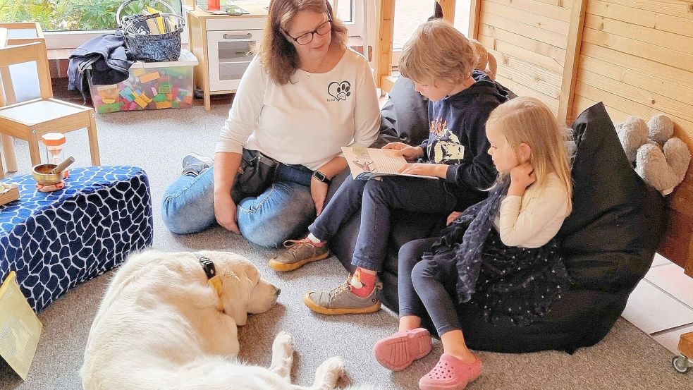 Theo liest dem Pädagogikbegleithund-Team Mala und Bärbel Tebben sowie seiner Schwester Merle vor. Foto: Käthe Dübbel