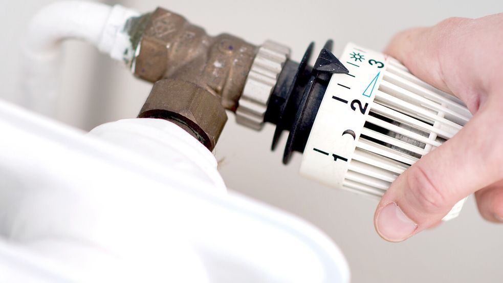 Ein Mann dreht am Thermostat einer Heizung. Foto: Hauke-Christian Dittrich/dpa