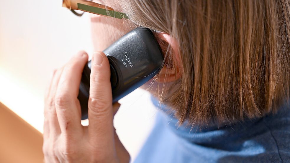 Eine Frau hält ein Festnetz-Telefon ans Ohr (gestellte Szene). Auch über das Haustelefon ist Banking möglich. Foto: Bernd Weißbrod/dpa