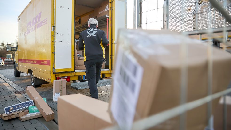Eine Mitarbeiterin der Deutsche Post DHL belädt ihr Fahrzeug mit Päckchen und Paketen. Foto: Jan Woitas/dpa
