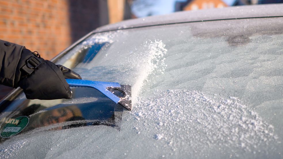 Eine Frau kratzt bei Temperaturen deutlich unter dem Gefrierpunkt Eis von der Windschutzscheibe eines Autos. Foto: Julian Stratenschulte/dpa