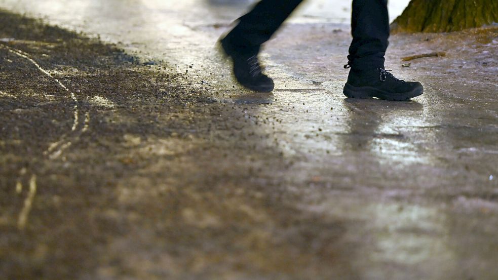 Ein Fußgänger läuft auf einem vereisten Gehweg. Foto: Lilli Förter/dpa