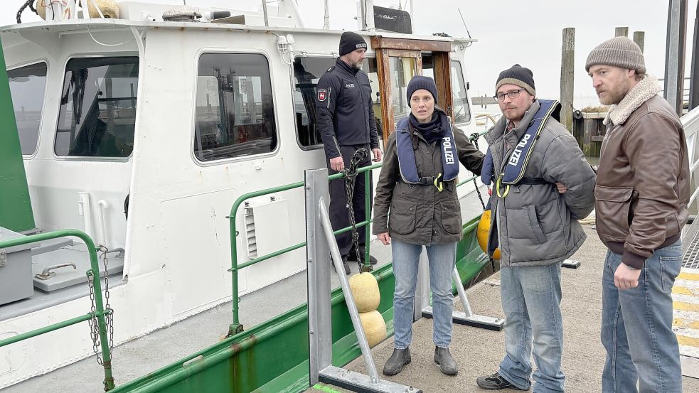 Im Bensersieler Hafen wartet das Polizeiboot mit Sven Kaiser (von links) auf Picco von Groote und Tom Radisch (rechts). Sie verkörpern die Rollen des beliebten Ermittlerduos Ann Kathrin Klaasen und Frank Weller, das Matti Schmidt-Schaller abführt. Foto: Susanne Ullrich