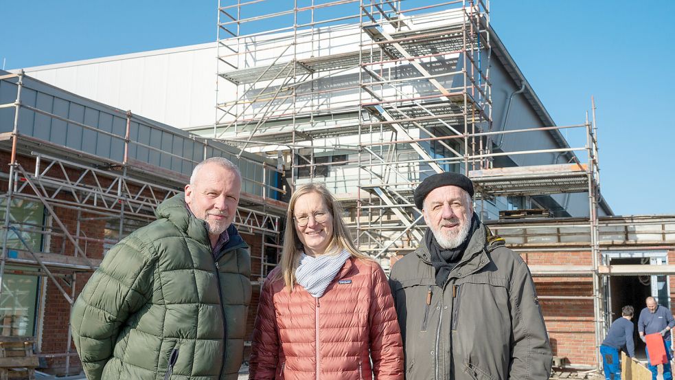 Bürgermeister Uwe Redenius (links), Projektplanerin Bettina Alberts-Tammena und Fachbereichsleiter Norbert Dubbels vor der Dreifachsporthalle in Hinte.