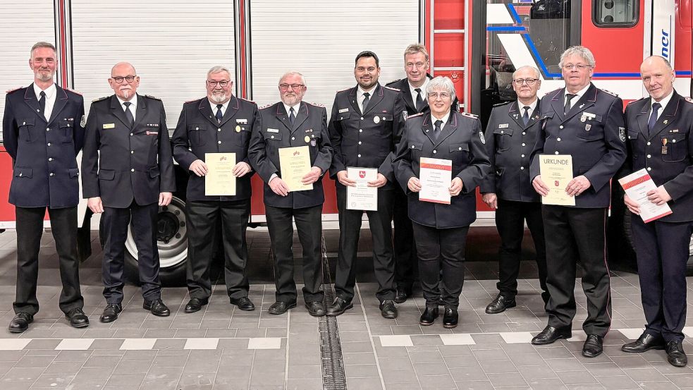 Gruppenbild mit Gratulanten und Geehrten: Andreas Harms (stellvertretender Stadtbrandmeister, von links), Abschnittsleiter Nord Peter Eggers, Heinrich Poppinga, Wilfried Rimbach, Aike Brinkmann, Ernst Berends, Sabine Kieviet, Karl-Heinz Grahl, Tjark Beckmann und Axel Held. Foto: Florian Ferber