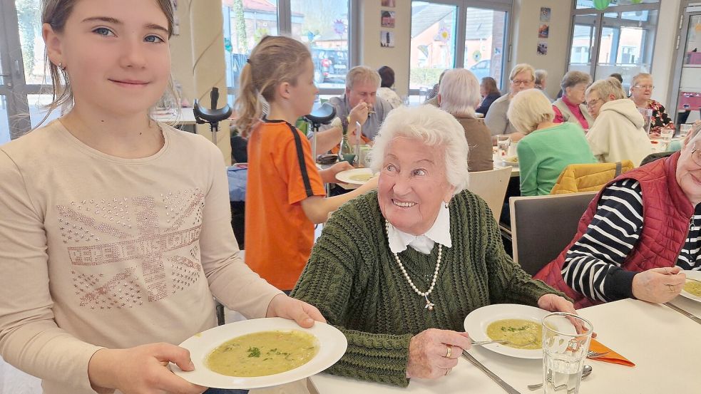 Kassandra (vorne) und Levin (im Hintergrund) helfen bei der Essensausgabe und essen auch mit, Dini Dams (sitzend, links) ist begeistert von dem Angebot in Bunde. Foto: Tatjana Gettkowski