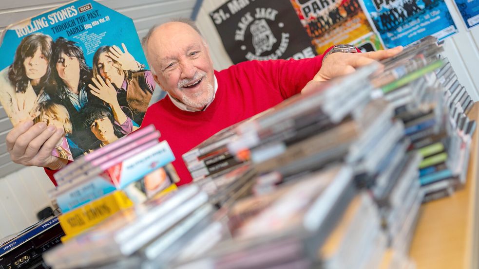 Friedrich Renken aus Remels sitzt vor einem Stapel CDs. Er hält einer seiner Lieblingsplatten von den Rolling Stones hoch. Foto: Klaus Ortgies