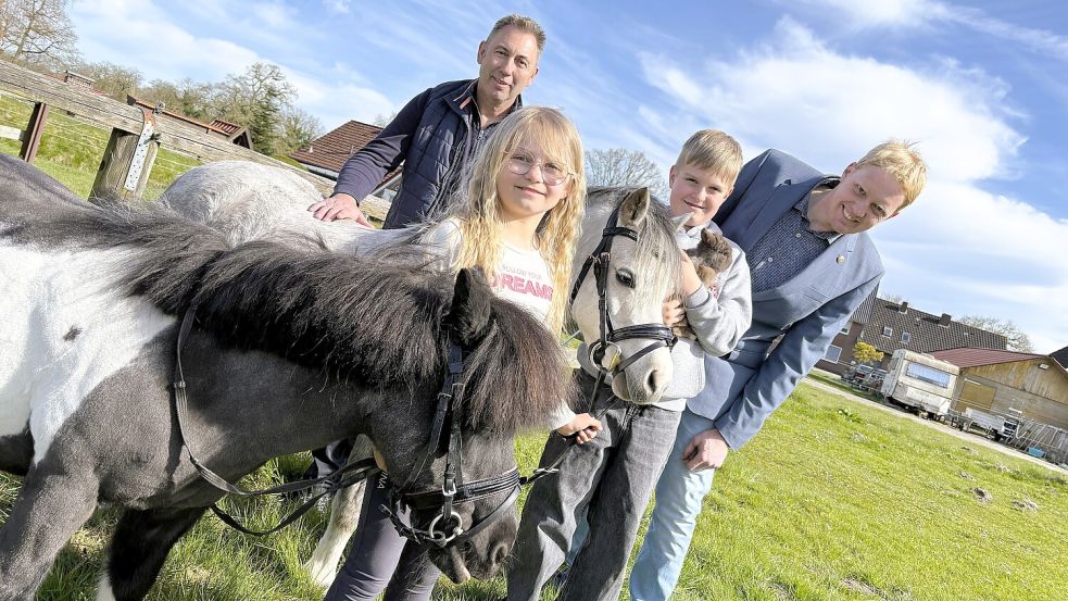 Marktmeister Erwin Onnen (links) und Ortsbürgermeister Heiko Hinrichs (CDU, rechts) mit Pony Trixie (von links), Indira de Vries, Pony Donner, Hendrik de Vries mit Kaninchen Paul auf dem Platz für den Viehmarkt in Bagband. Foto: Nicole Böning
