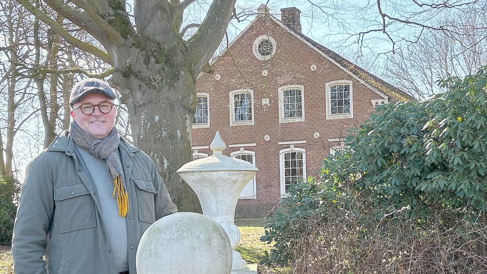 Kai Nilson unter der großen Buche, die für den Buchenhof namensgebend war. Der 2021 verstorbene Vorbesitzer Konrad Onnen hat auch den Zugang von der Straße aus über eine kleine Holzbrücke mit seinen Betonskulpturen gestaltet. Foto: Susanne Ullrich