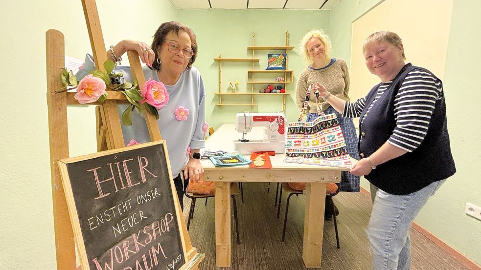 „Hier entsteht unser neuer Workshop-Raum“, steht auf der Tafel am Eingang im neu gestalteten Raum in Wiesmoors Kreativ-Laden „Kreuz & Quer“. Rita Durka (von links), Ilse van Opzeeland und Helga Saathoff stellten das neue Konzept vor. Foto: Nicole Böning