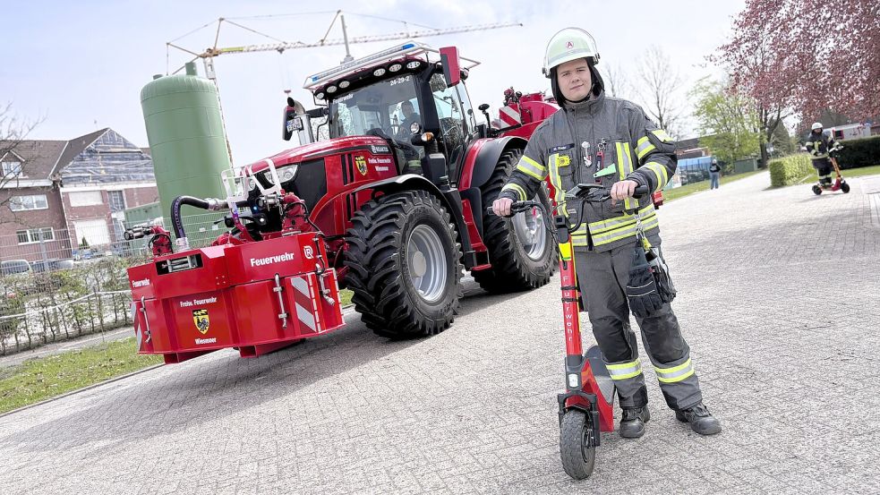 Maximilian Keller mit einem Einsatz-Scooter der Freiwilligen Feuerwehr Wiesmoor – im Hintergrund der „Superstar“ der Wehr: der Einsatz-Traktor. Foto: Nicole Böning