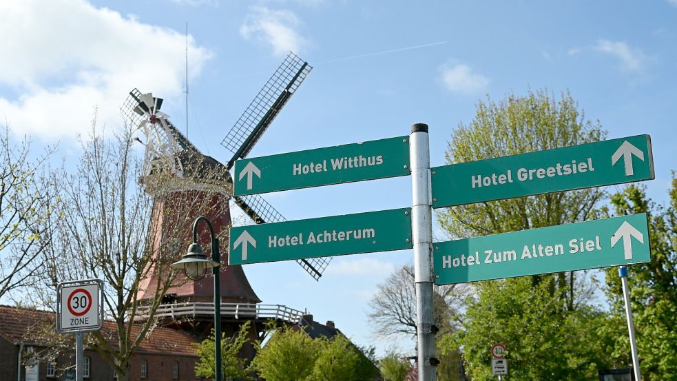 Schilder weisen den Weg zu Hotels in Greetsiel. Im Hintergrund ist die rote Mühle zu sehen. Foto: Heinz Wagenaar