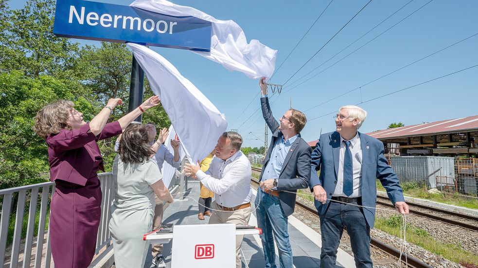 Symbolisch enthüllten die Ehrengäste das Schild des Bahnhaltespunkts Neermoor. Es löste sich allerdings nicht so leicht, wie anfangs erhofft. Das Bild zeigt (von links): Carmen Schwabl (LNVG), Barbara Schneider (Westfalenbahn), Robert Guggenberger, Stefan Wey (beide DB Infrago), sowie Bürgermeister Hendrik Schulz und Ortsbürgermeister Berthold Koch. Foto: Klaus Ortgies