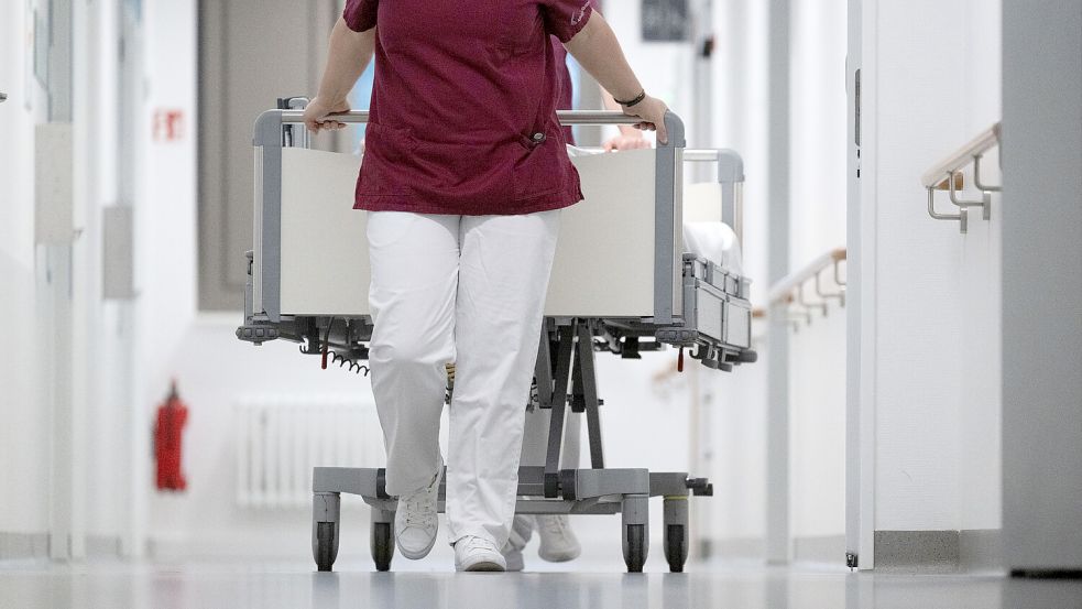 Eine Krankenpflegerin und ein Krankenpfleger schieben ein Krankenbett durch den Gang einer Station eines Krankenhauses. Foto: Marijan Murat/dpa
