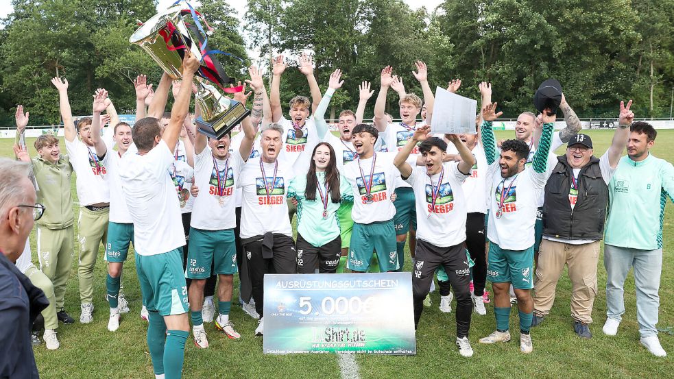 Da ist das Ding: Michael Olbrys stemmt den Pokal in die Höhe- GW Firrel ist die erste Mannschaft, die den Titel beim Ostfriesland-Cup verteidigen konnte. Foto: Jens Doden/ Emden