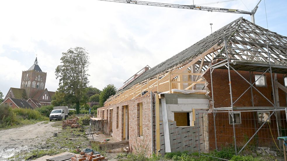 Links die Kirche, rechts die Baustelle: Im nächsten Frühjahr sollen, wenn das Wetter mitspielt, die Bauarbeiten an dem alten Gulfhof in Pilsum abgeschlossen sein. Fotos: Heinz Wagenaar
