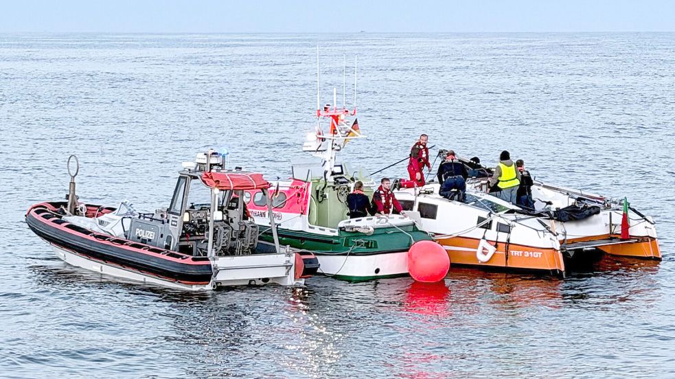 Am havarierten Katamaran (rechts) sind das Tochterboot „Johann Fidi“ des Seenotrettungskreuzers „Bernhard Gruben“ der DGzRS sowie das Kontrollboot des Einsatzschiffes der Bundespolizei „Bad Düben“ eingetroffen. Seenotretter und Polizisten kümmern sich gemeinsam um den gebrochenen Mast und das Segel. Foto: Die Seenotretter – DGzRS