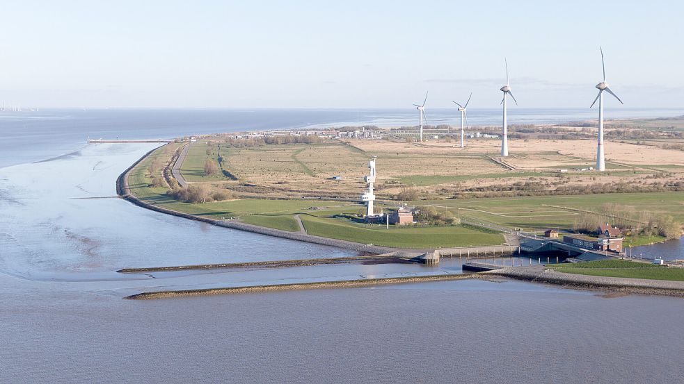 Braucht spätestens für den Militärhafen eine neue Zuwegung: der Rysumer Nacken. Im Bild sind rechts das Siel- und Schöpfwerk Knock und in der Mitte die Verkehrszentrale des Wasserstraßen- und Schifffahrtsamts zu sehen. Links daneben sollen die Pieranlagen für die Militärschiffe gebaut werden. Foto: Tobias Bruns/dpa